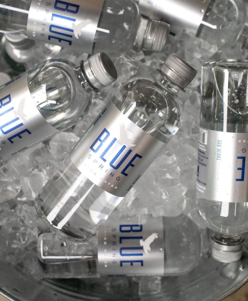 Blue Spring Water bottles chilled on ice, featuring premium bottled spring water now available at Russell's Piggly Wiggly.